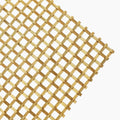 Gold-toned woven stainless steel decorative wire grille panel, close-up of interlocking flat metal bands and round wires
